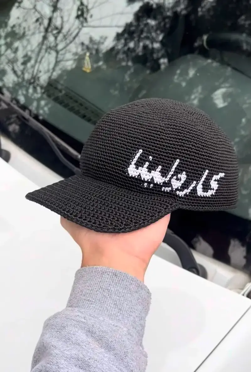 Boné de crochê preto com letra árabe visto de frente